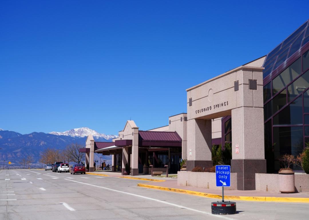 A small Colorado Springs airport building in front of blue sky and mountains.