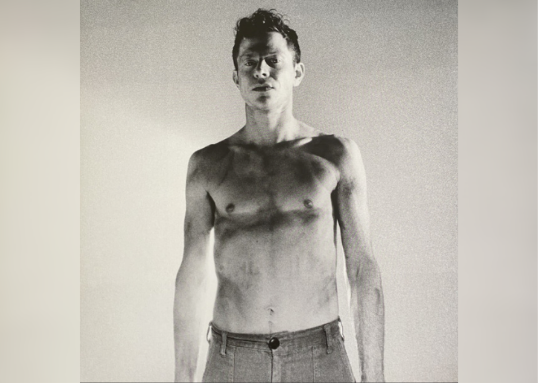 A man wearing jeans and no shirt in black and white.