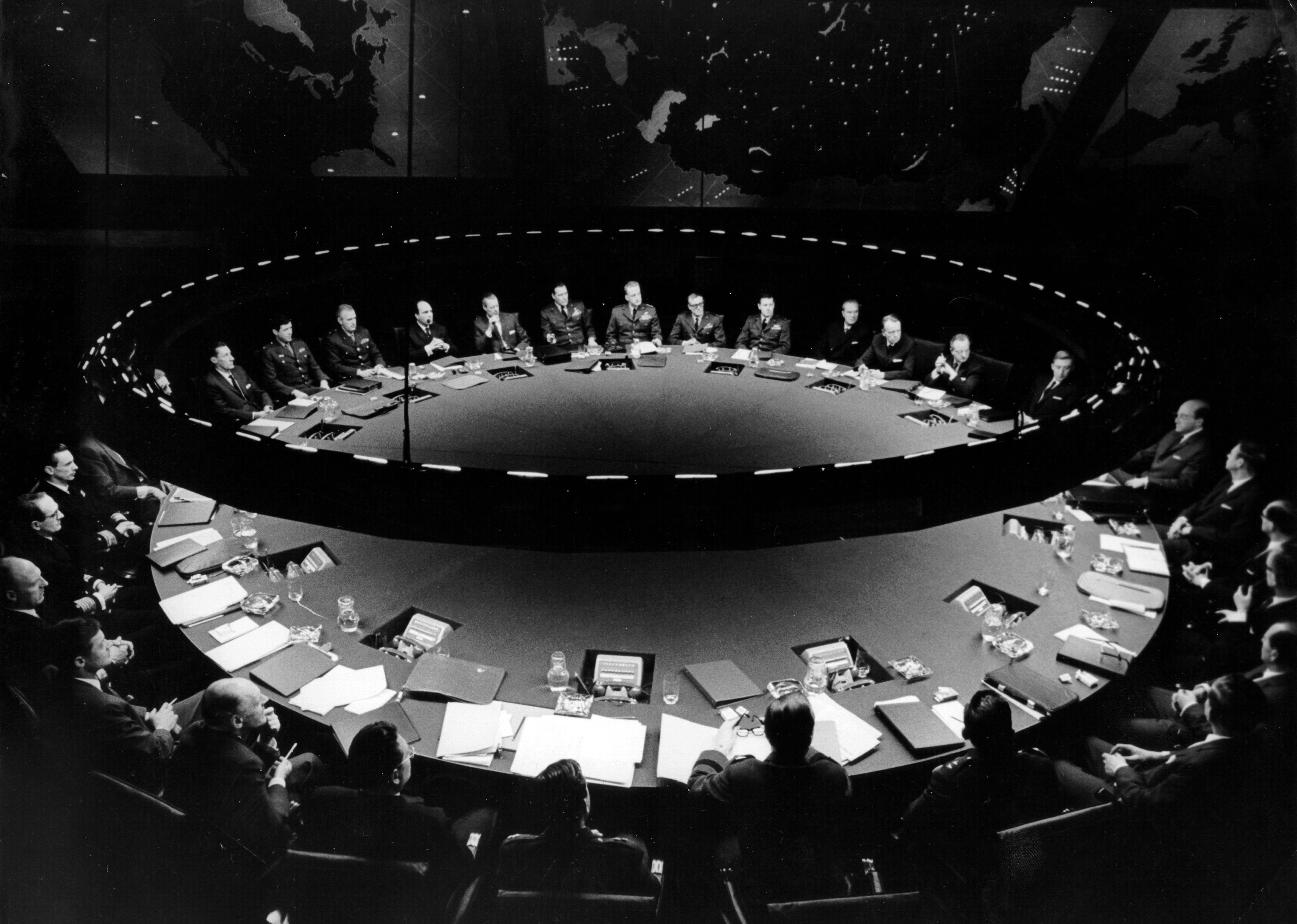 A large round table of men in military uniforms and suits.