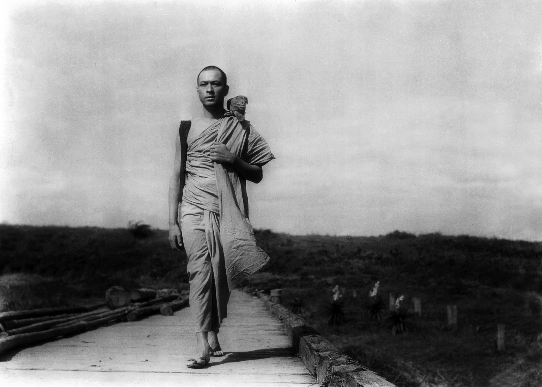 A man dressed as a monk walking on a path.