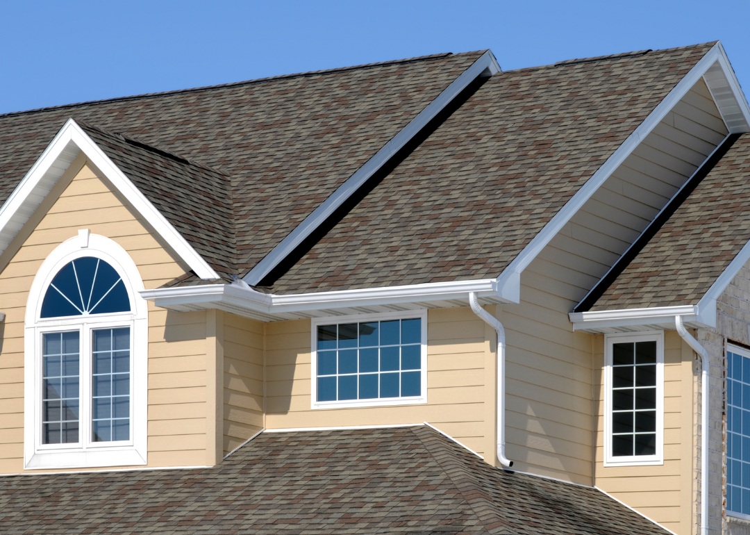 The second story of a beige home with big windows.