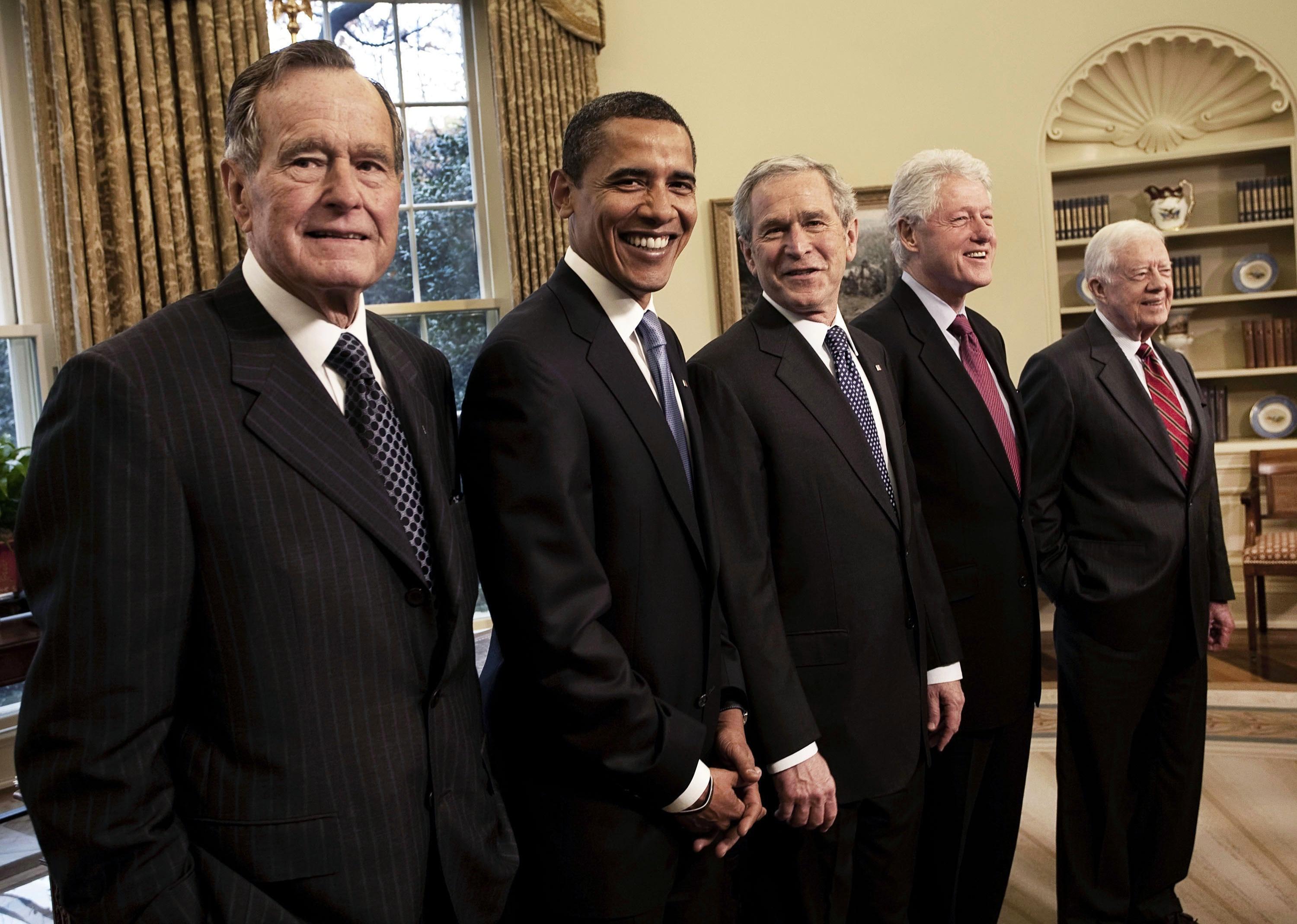 George Bush, Barack Obama, George W. Bush, Bill Clinton and Jimmy Carter standing in a line in the Oval Office at the White House.