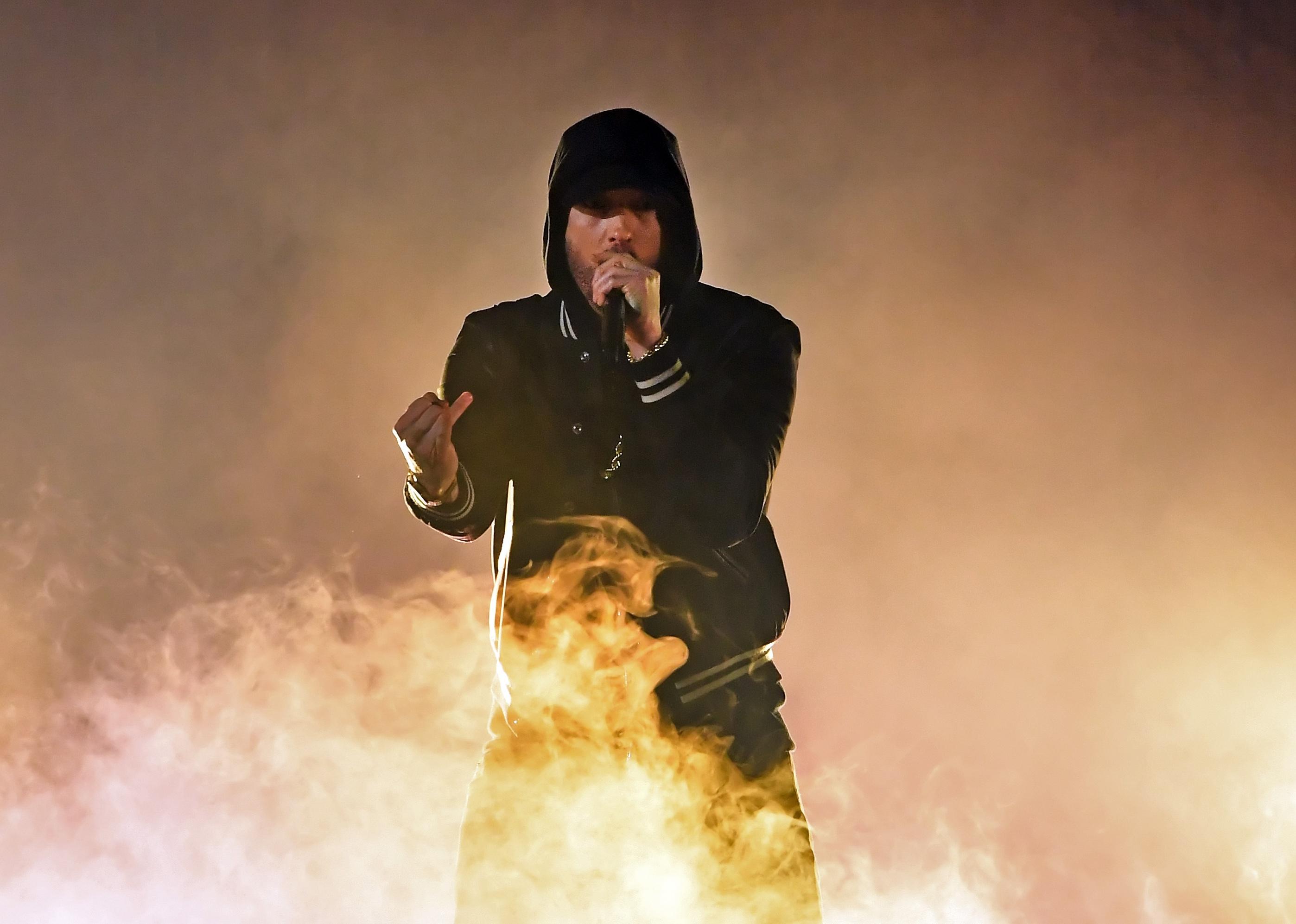 Eminem performing in all black with yellow smoke in front