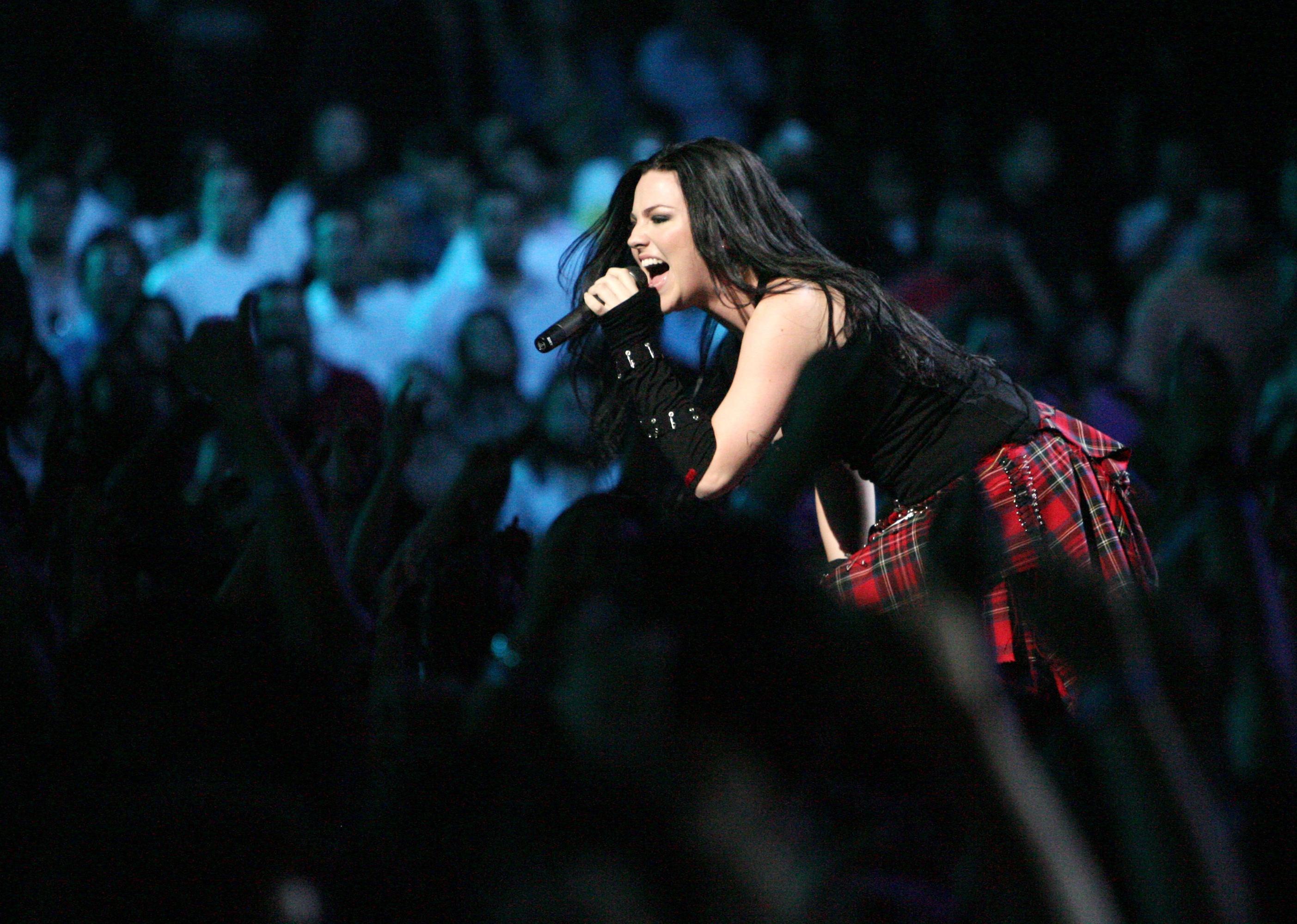 Evanescence in a black top and plaid skirt performing