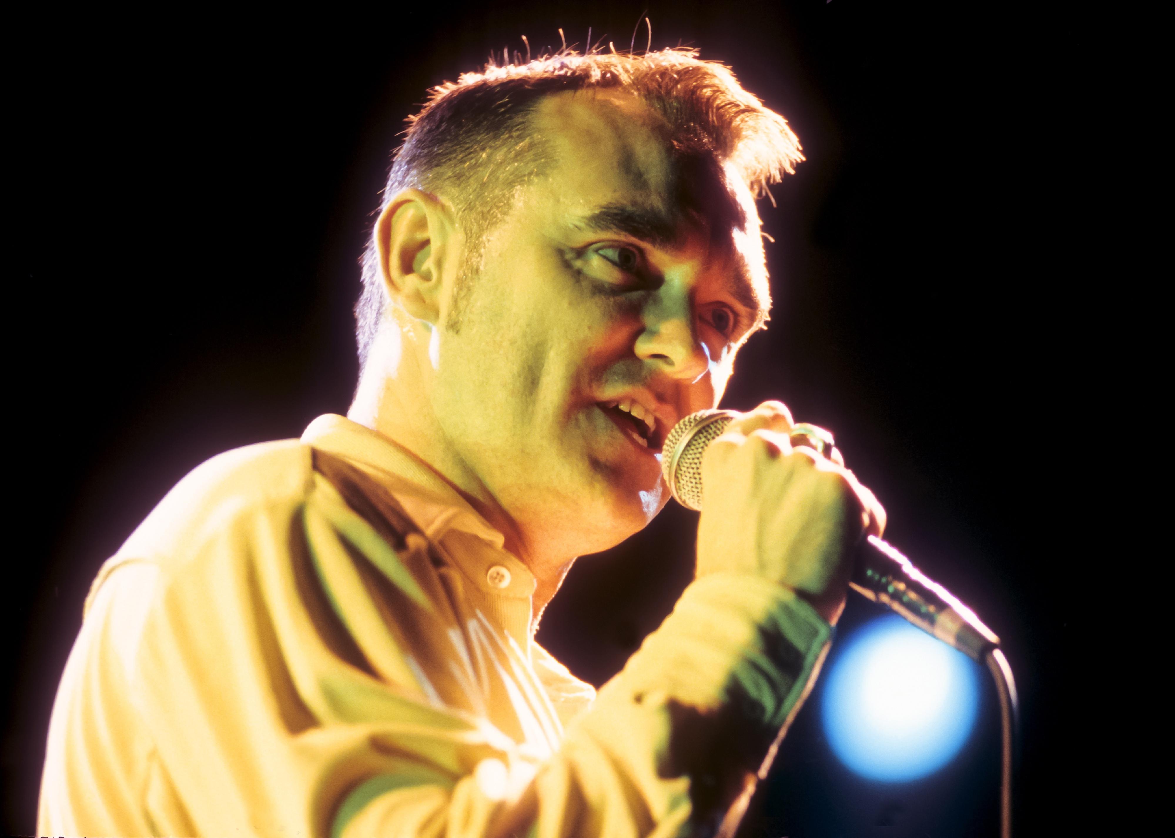 Morrissey performing under a yellow light.