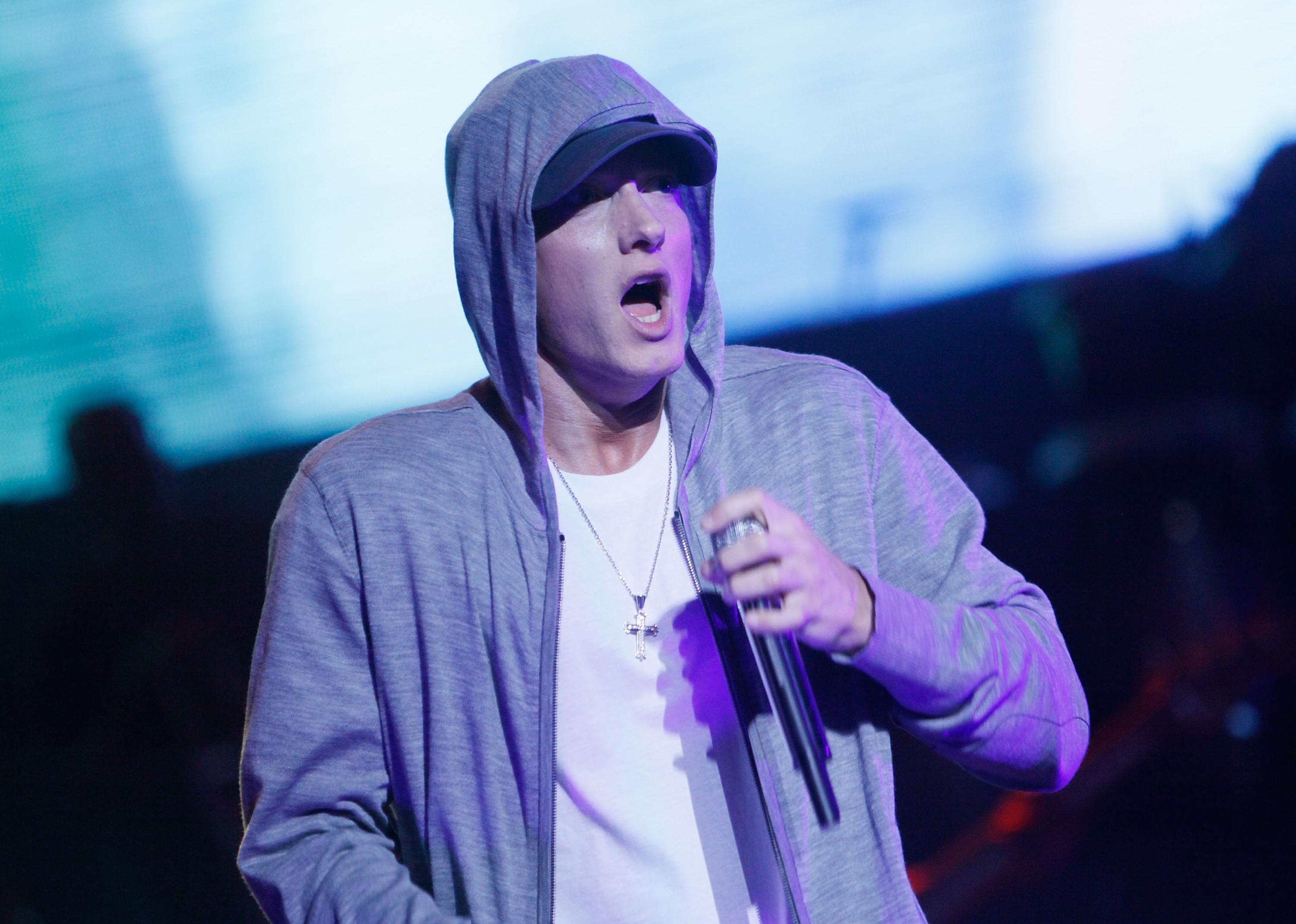Eminem onstage in a hoodie and hat.