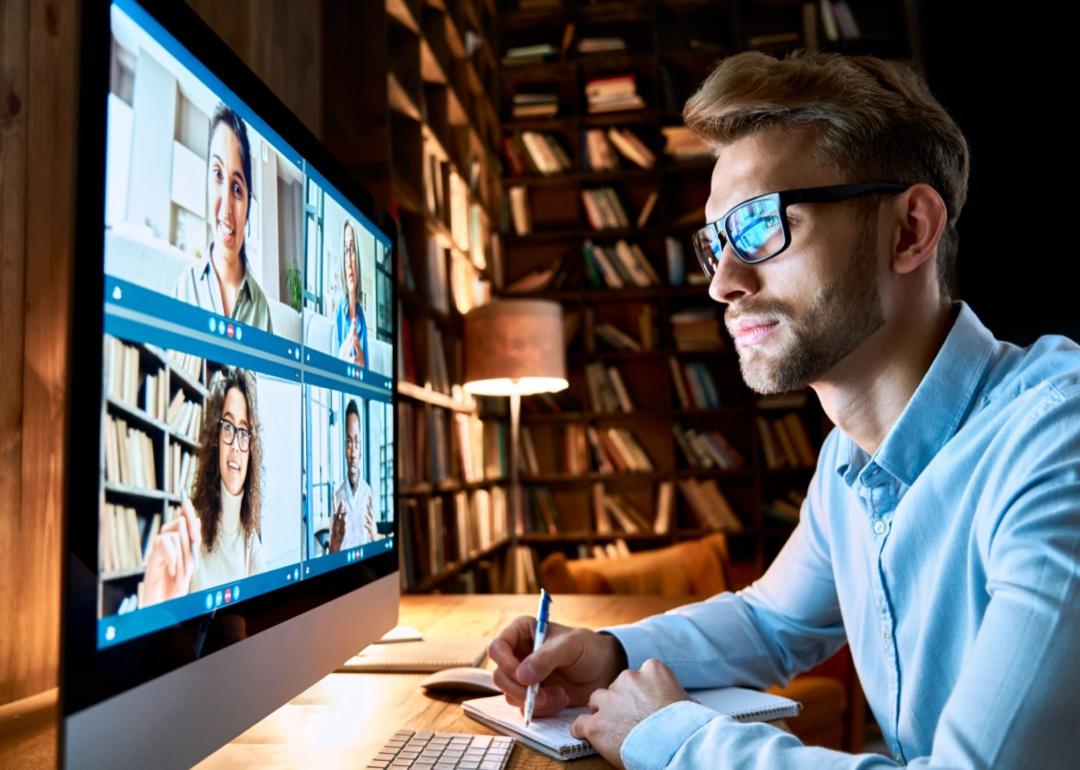 A man in an office with books on shelves in the background on a Zoom meeting.