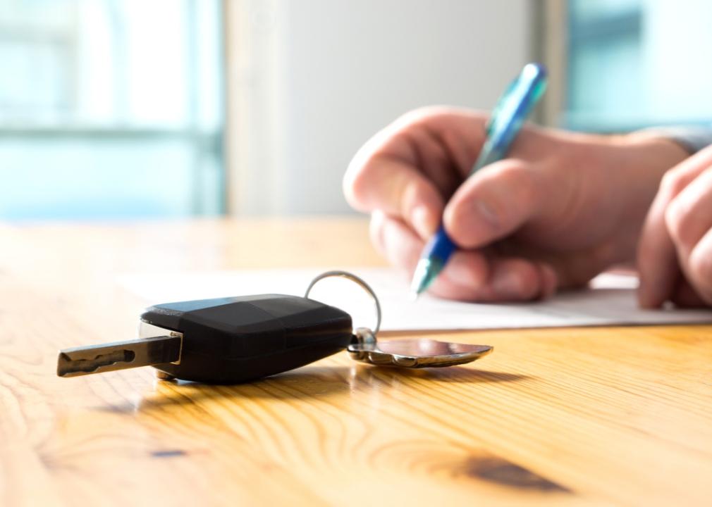Car key on a table with paperwork being signed.