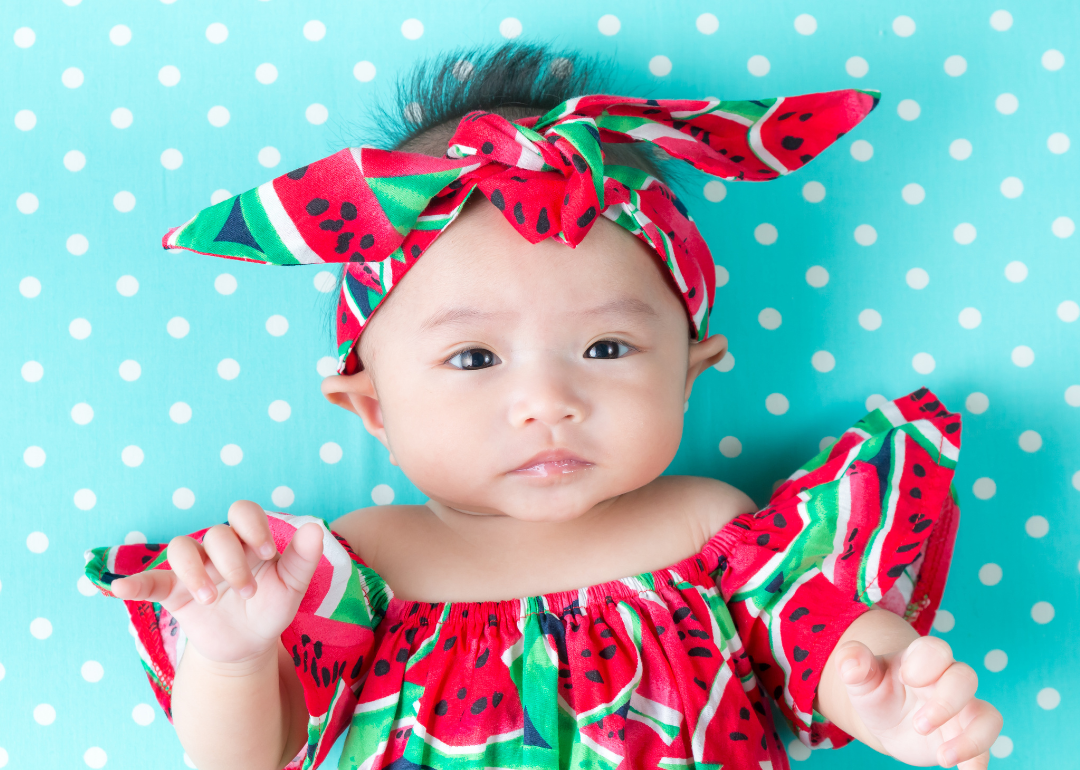 A baby in a watermelon outfit and headband.