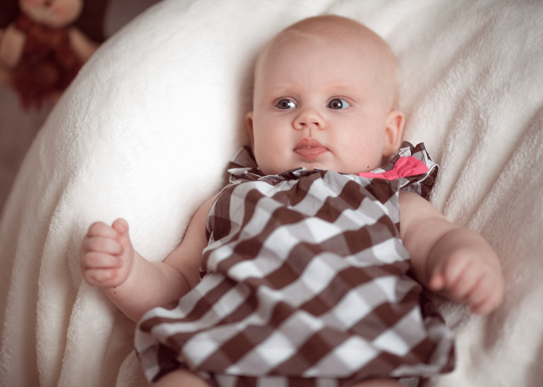 A baby girl in a brown and white checkered outfit.