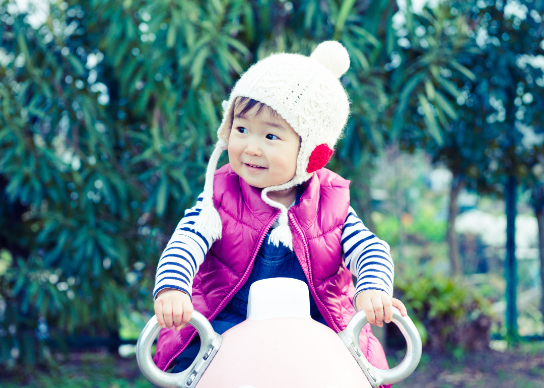 A baby girl in a pink vest and knit hat.