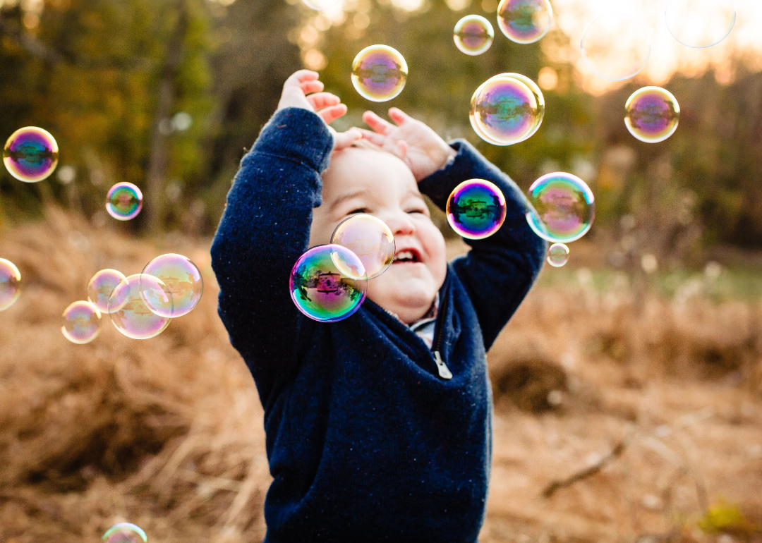A baby boy in a blue sweater playing with bubbles.
