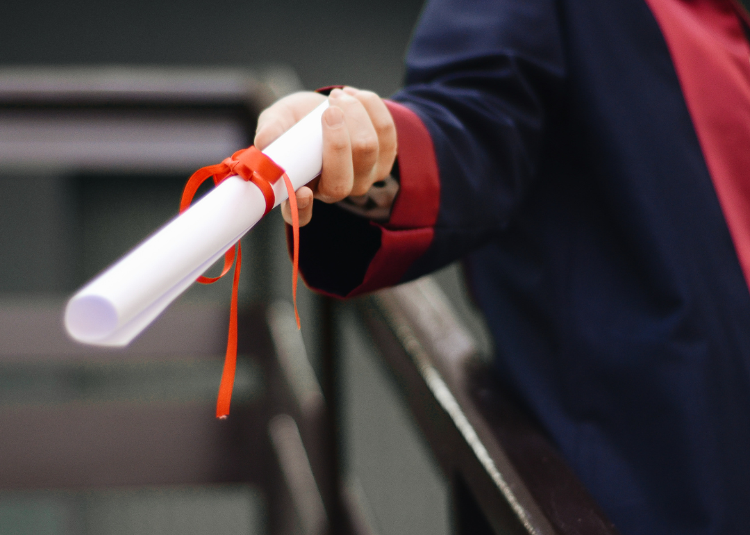 Person holding a white diploma with bow.