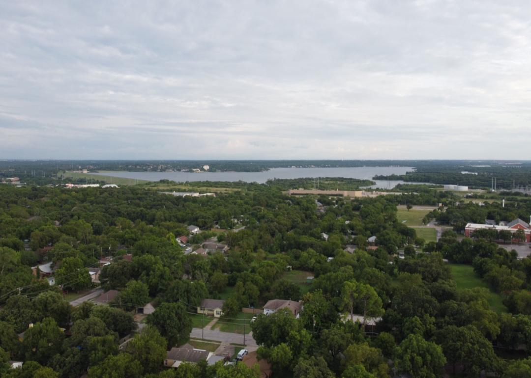 An aerial view of homes surrounded by trees with a lake in the background.
