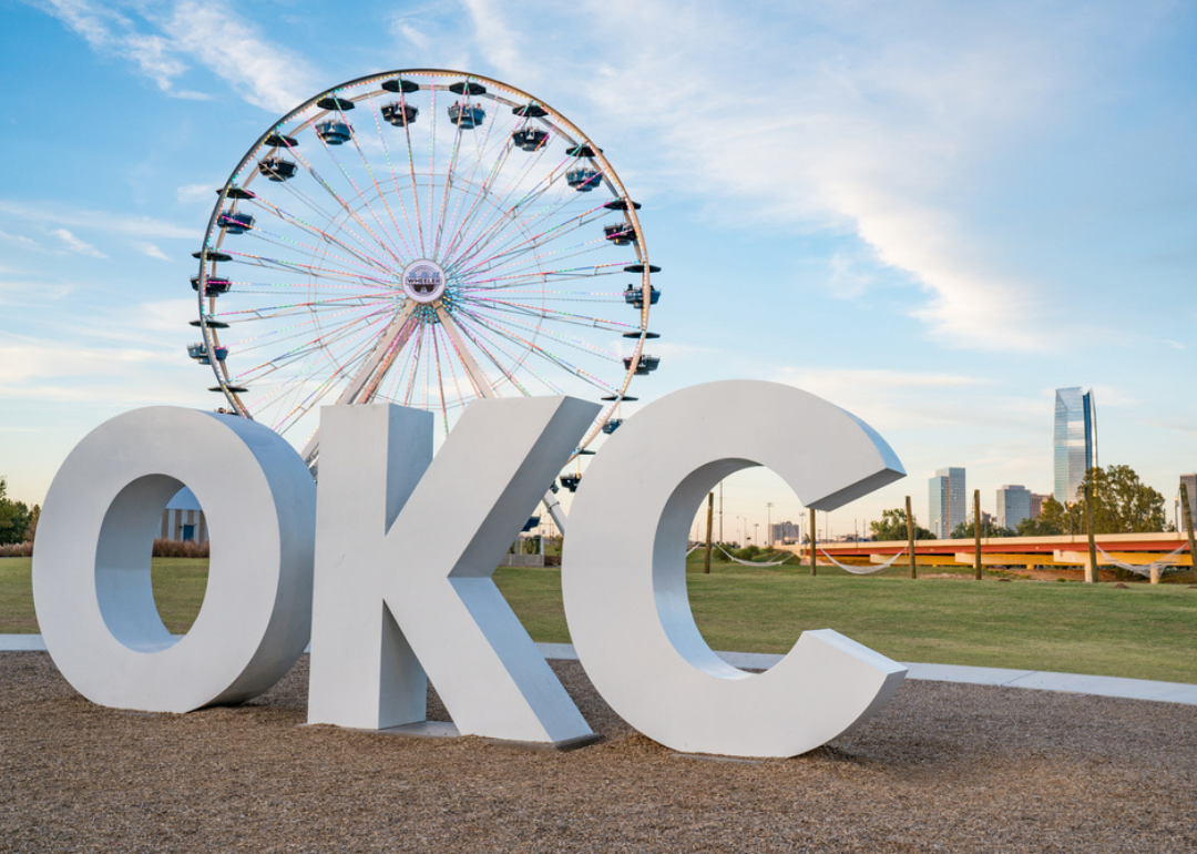An OKC sign in front of a ferris wheel.