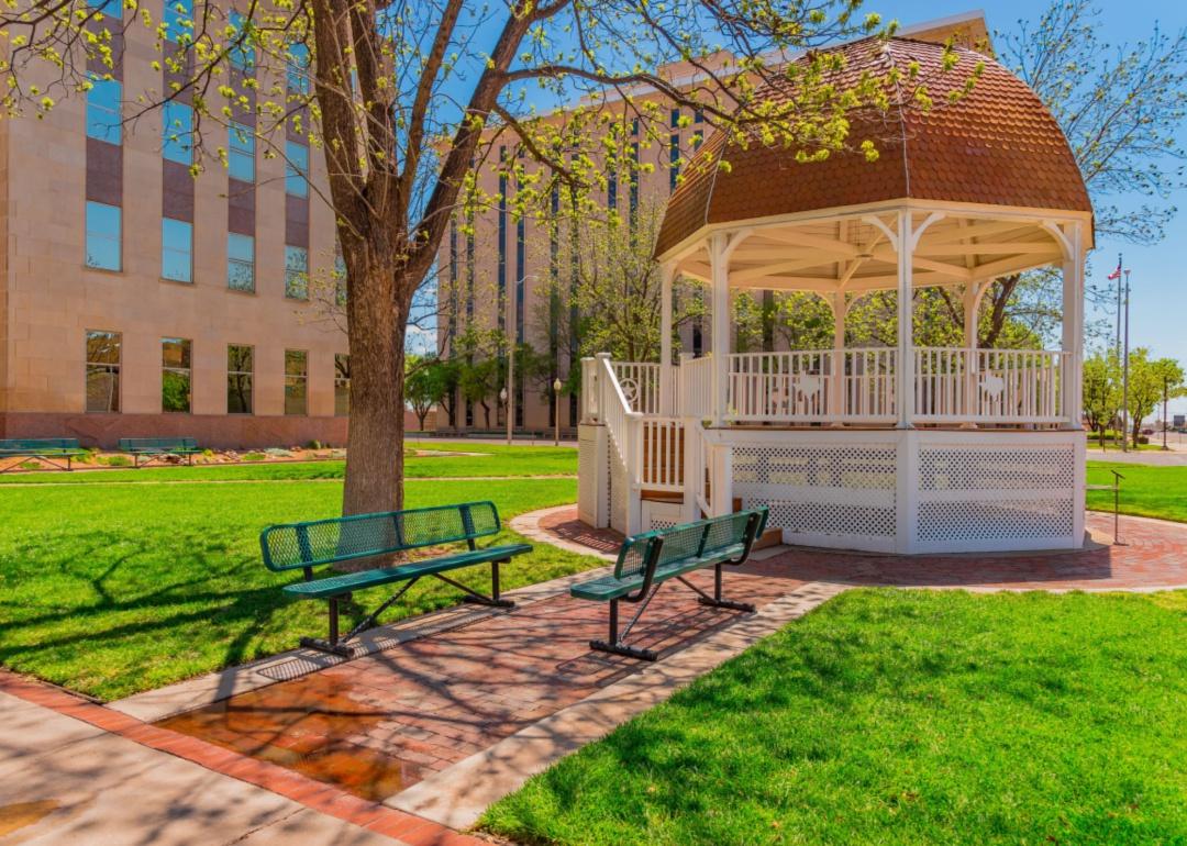 A gazebo in a park in front of some buildings.