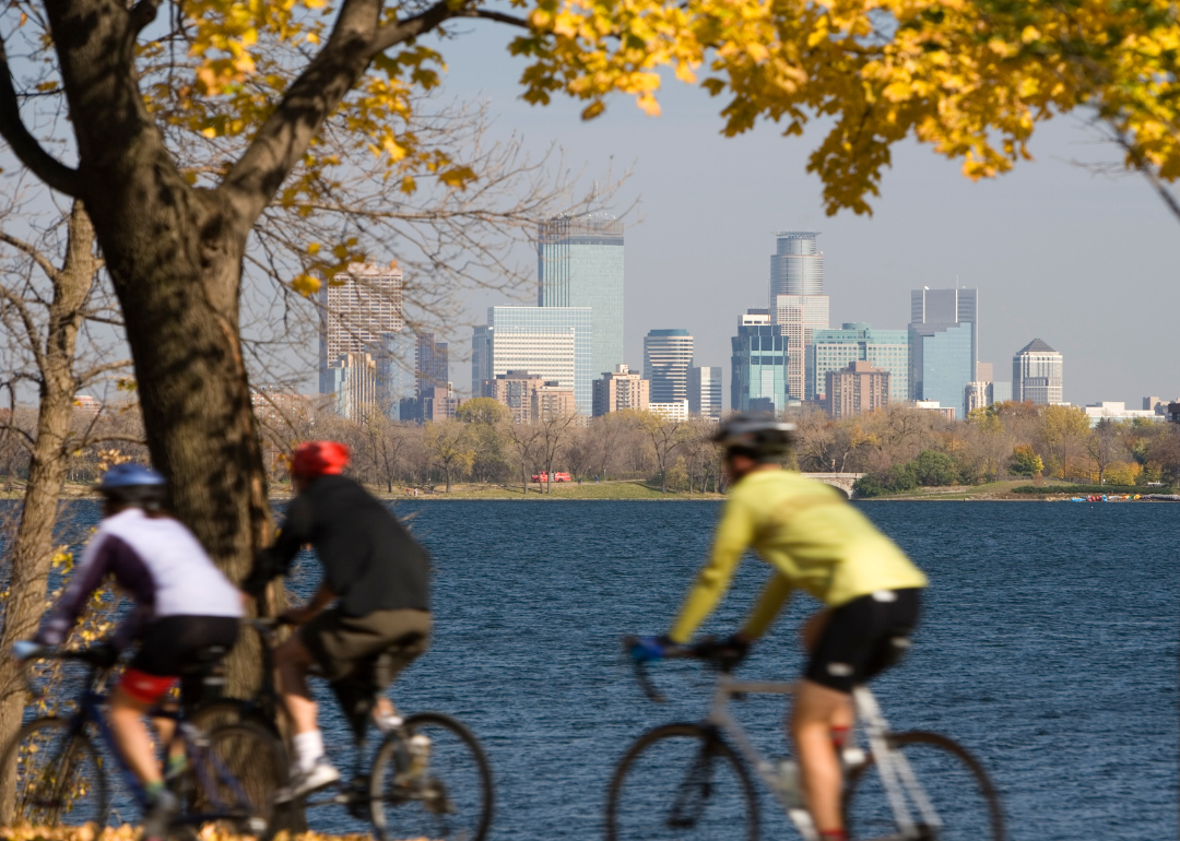 Cyclists on a trail with downtown across the water.