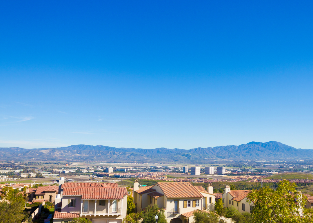 Large homes in the hills with downtown and mountains in the background.