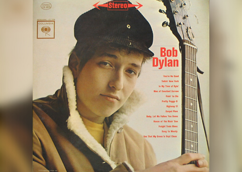 Close-up of a young Bob Dylan with the top of his guitar standing up.