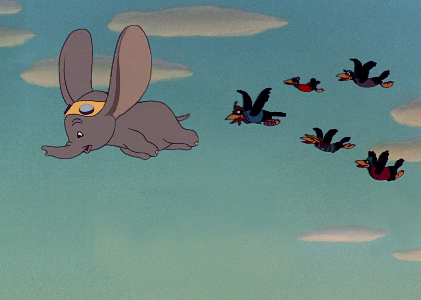 Dumbo flies with crows in a film still from ‘Dumbo.