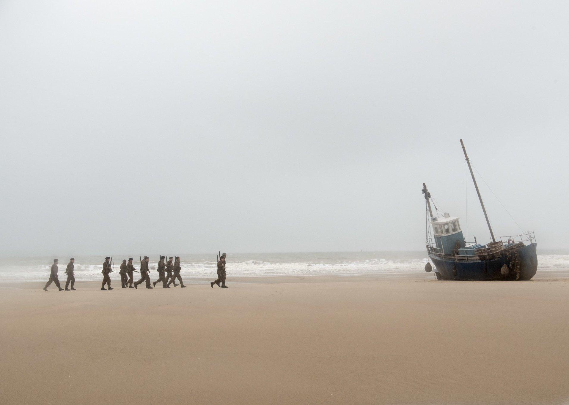 Actors playing Allied soldiers march on the beach in a scene from ‘Dunkirk.