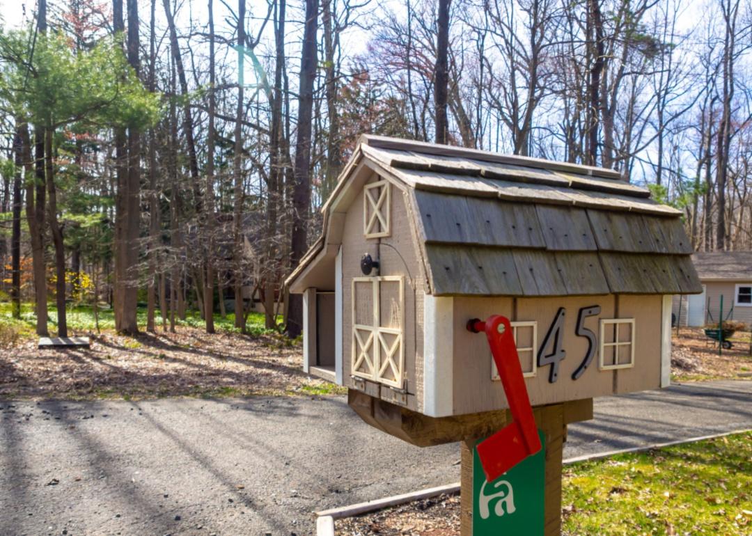 A tan mailbox shaped like a barn.