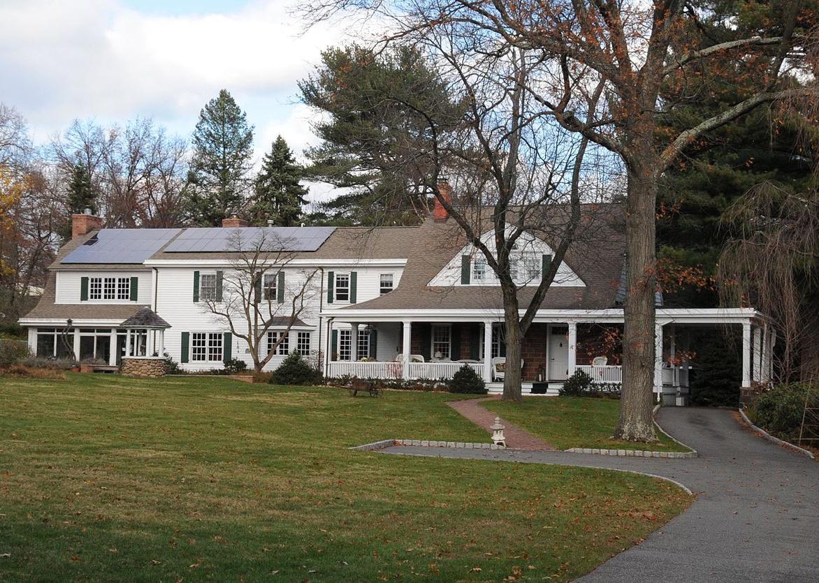 A large historic colonial home with solar panels on the roof.