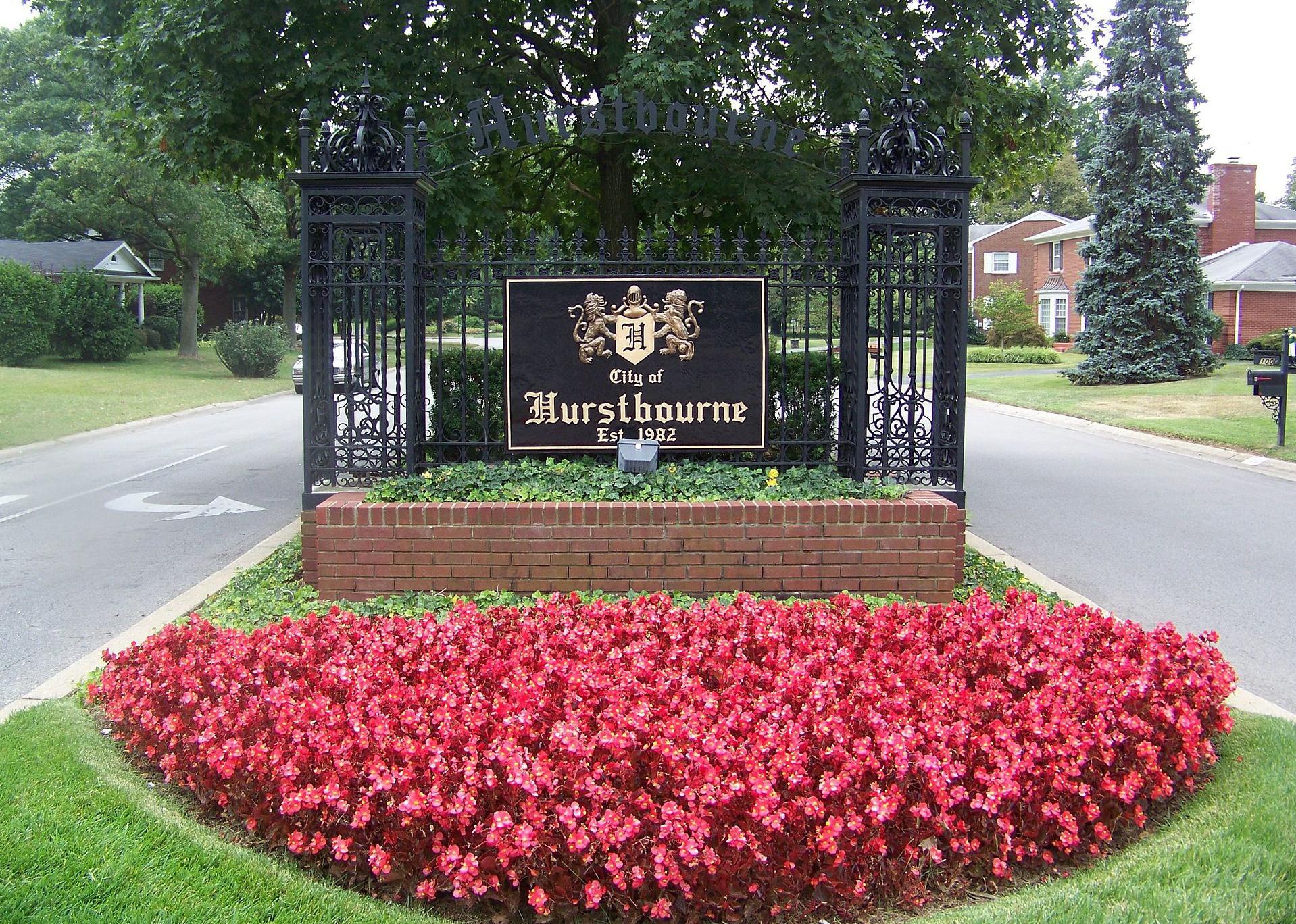 An iron entrance into Hurstbourne with pink flowers in the front.