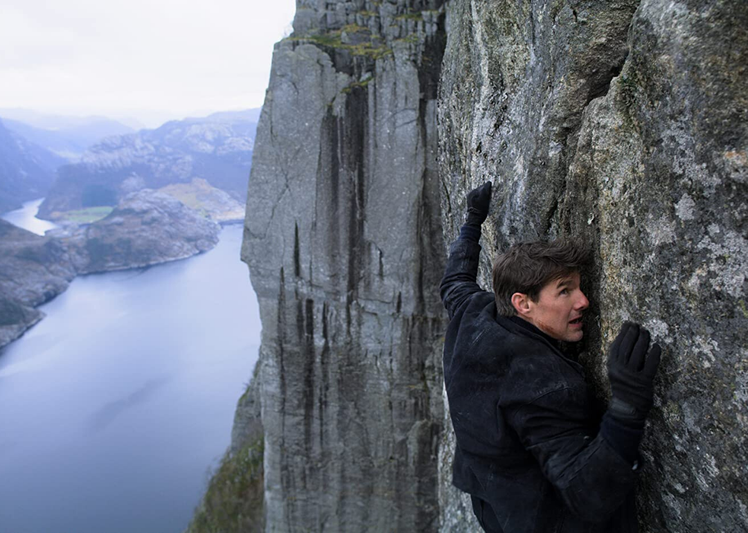 Tom Cruise scaling the side of a mountain.