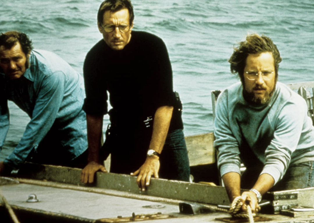 Richard Dreyfuss, Roy Scheider, and Robert Shaw in a boat looking at something in the water.