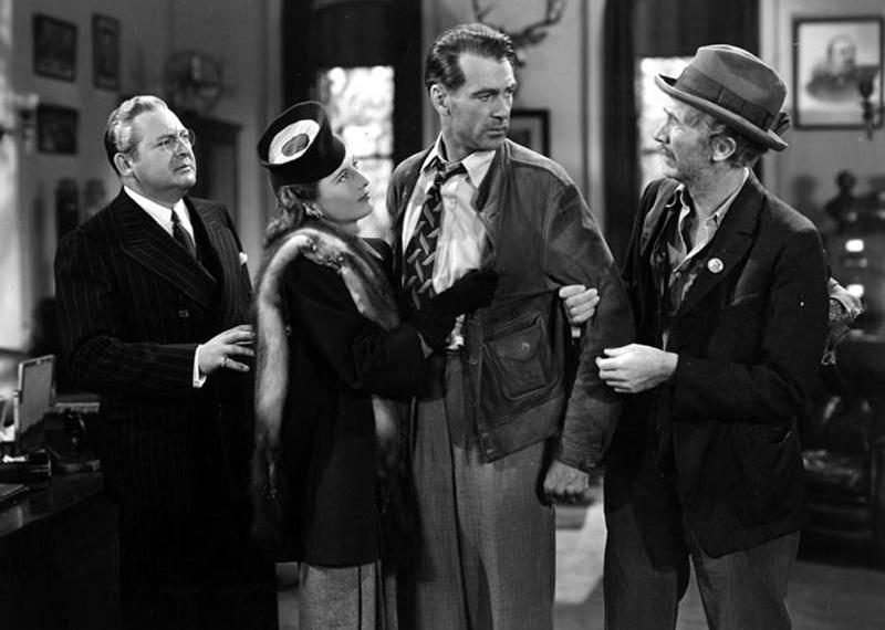 Walter Brennan, Barbara Stanwyck, and Edward Arnold standing in a line looking seriously at Gary Cooper.