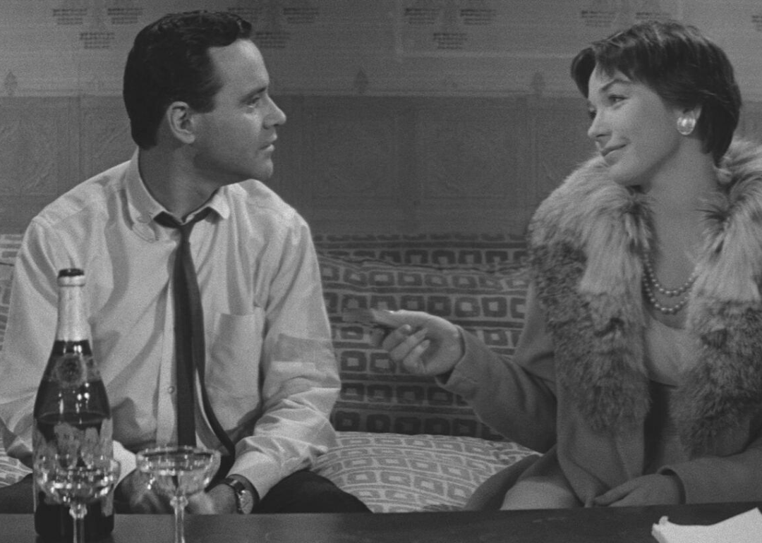 Jack Lemmon and Shirley MacLaine sitting on a couch dressed up with Champagne on the coffee table.