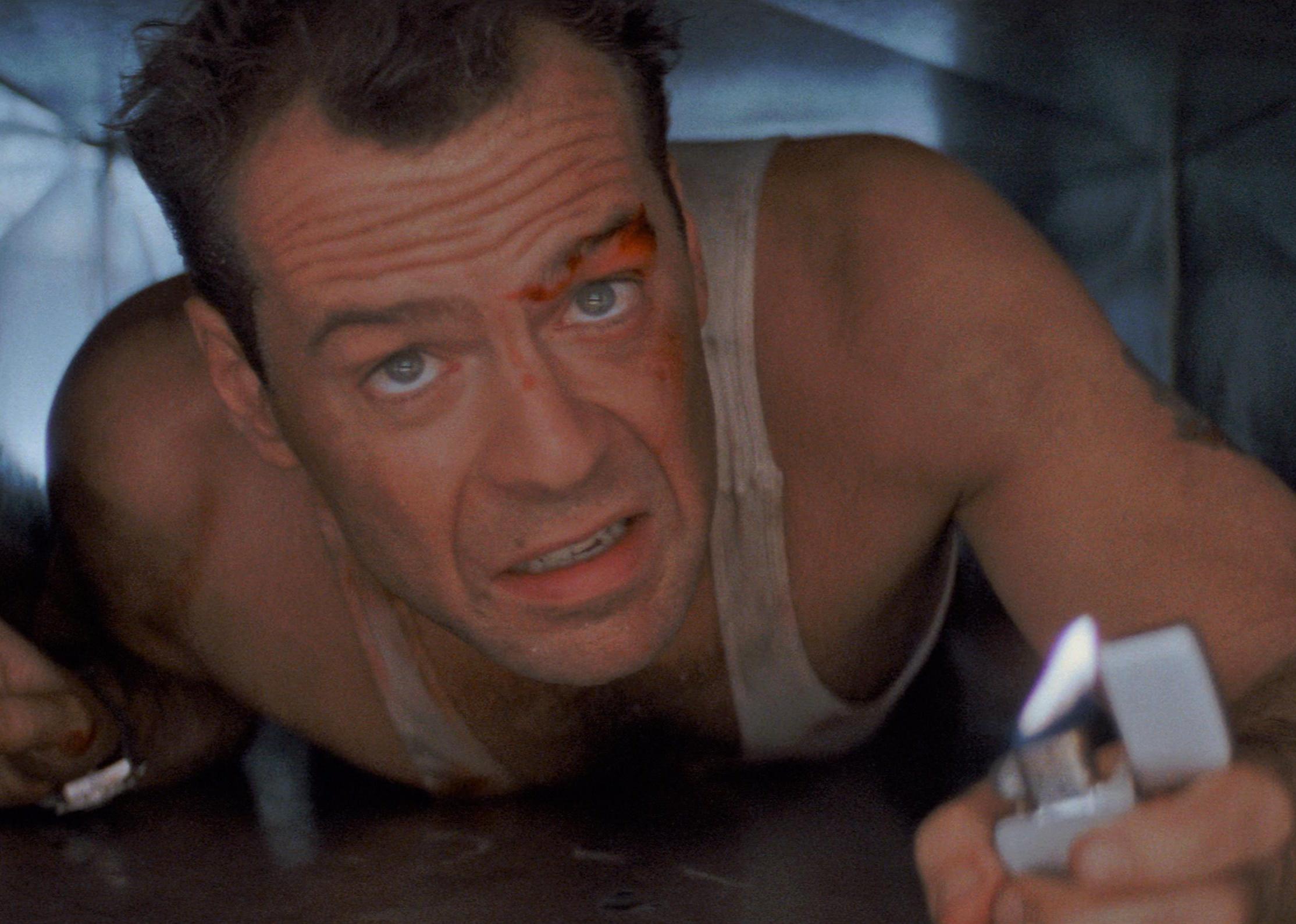 Bruce Willis crawling through a tiny space with a lighter.