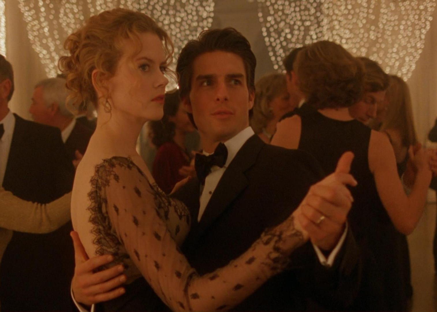 Tom Cruise and Nicole Kidman dressed up and dancing in a ballroom full of lights.