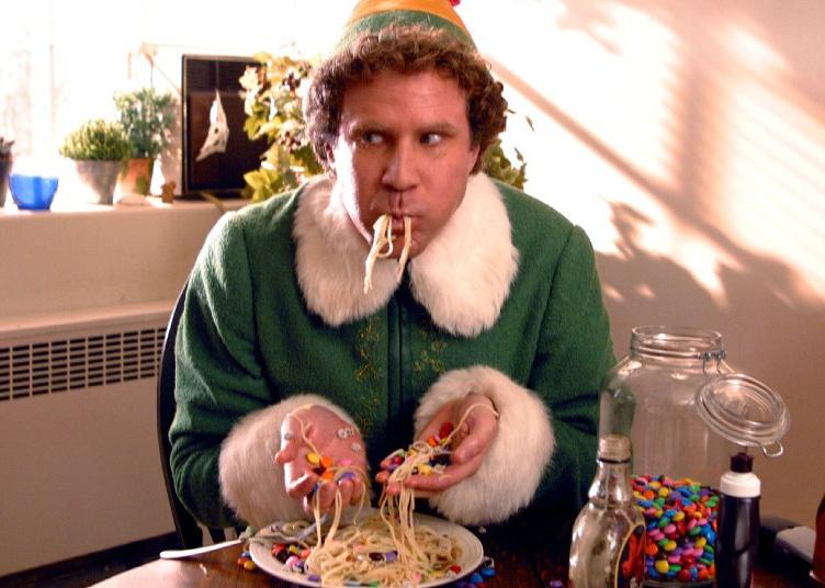 Will Ferrell, in an elf suit, eating spaghetti with candy.