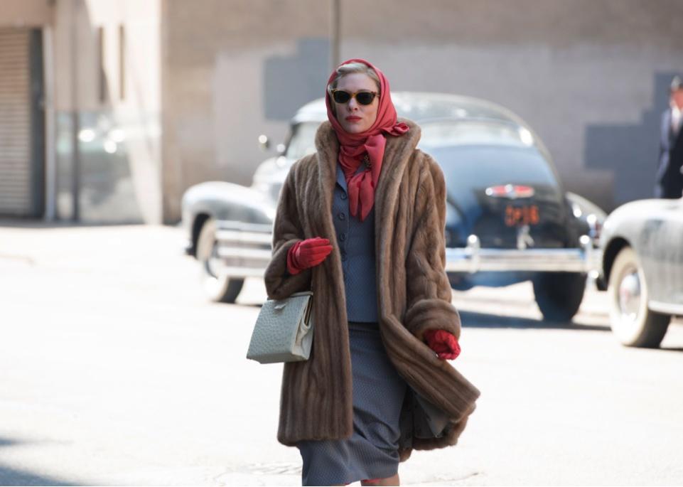Cate Blanchett walking across the street in a fur coat and scarf.
