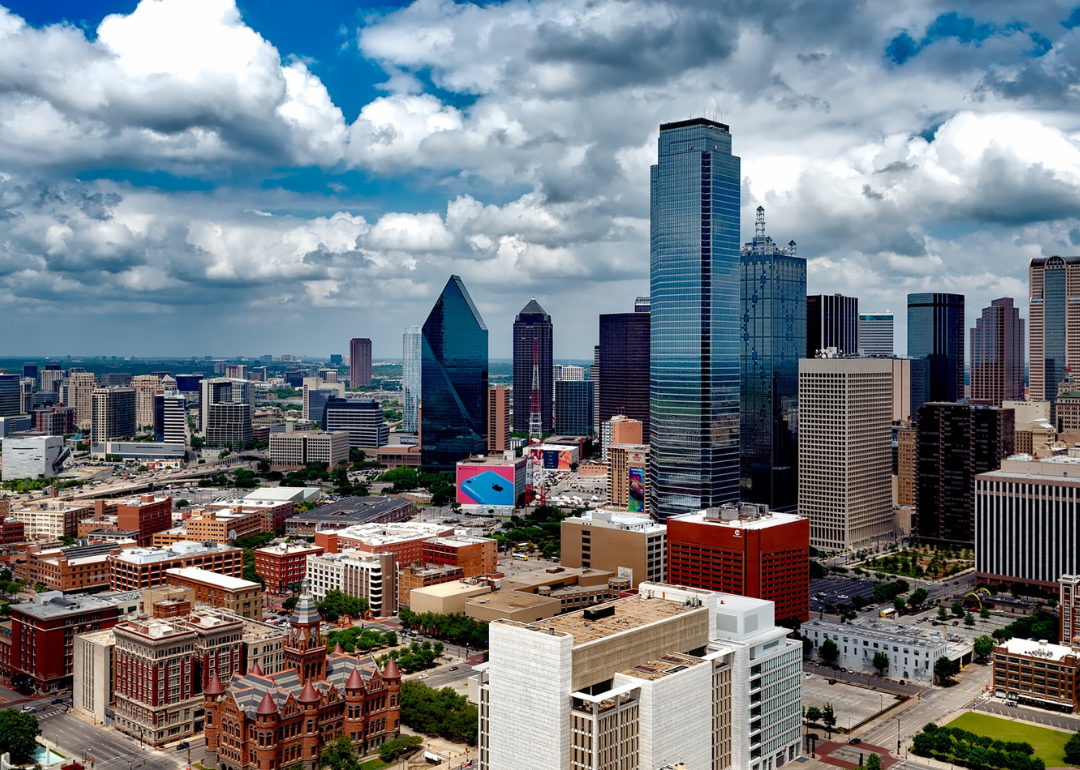 Downtown Dallas, TX skyline with a blue sky and clouds above.