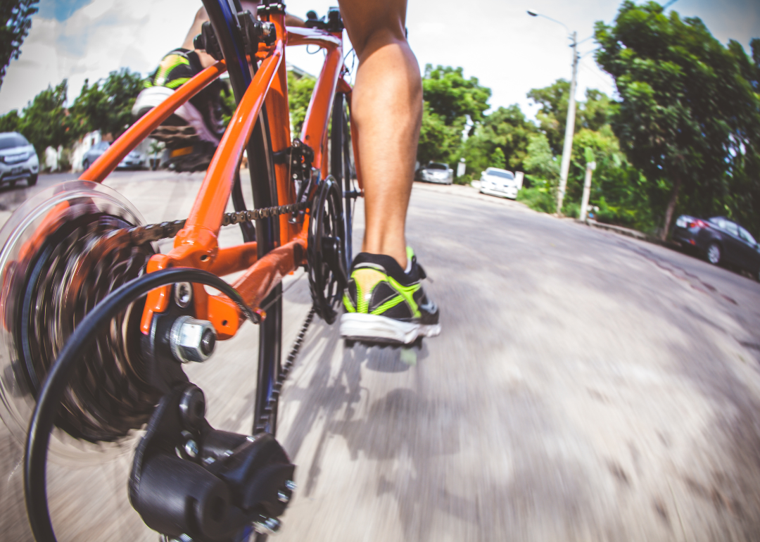 A close-up of a person's leg riding a bicycle in the city.