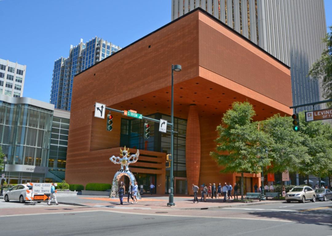 A silver and gold sparkling art sculpture and pedestrians in front of a museum.