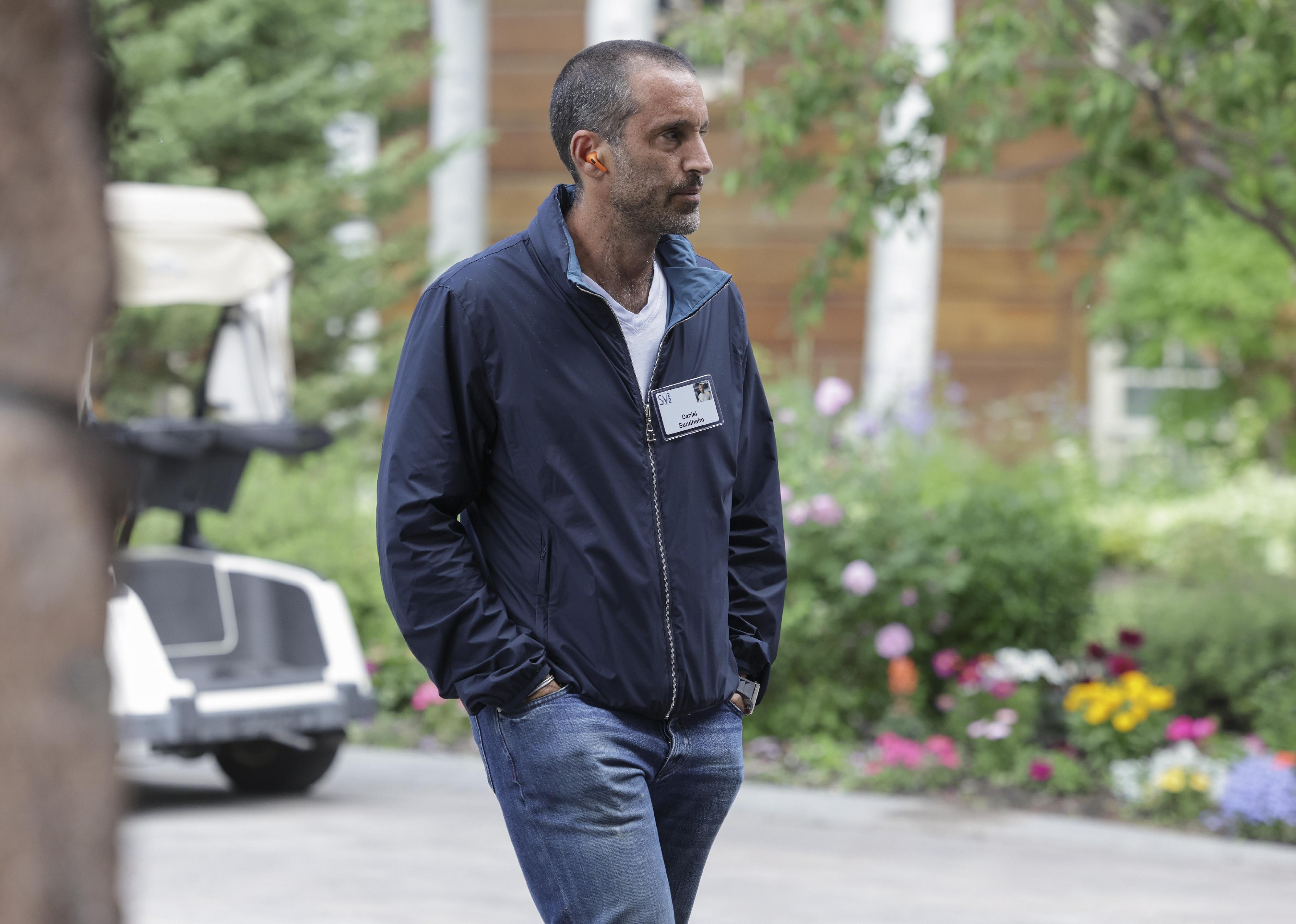 Daniel Sundheim walking outside in a blue jacket and jeans.
