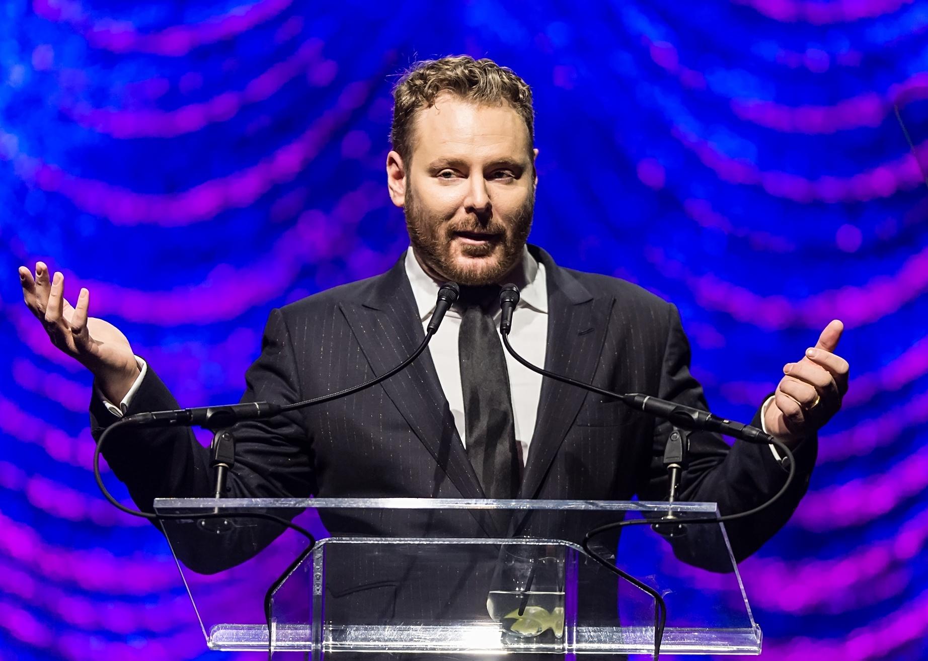 Sean Parker in a black suit speaking at a podium.