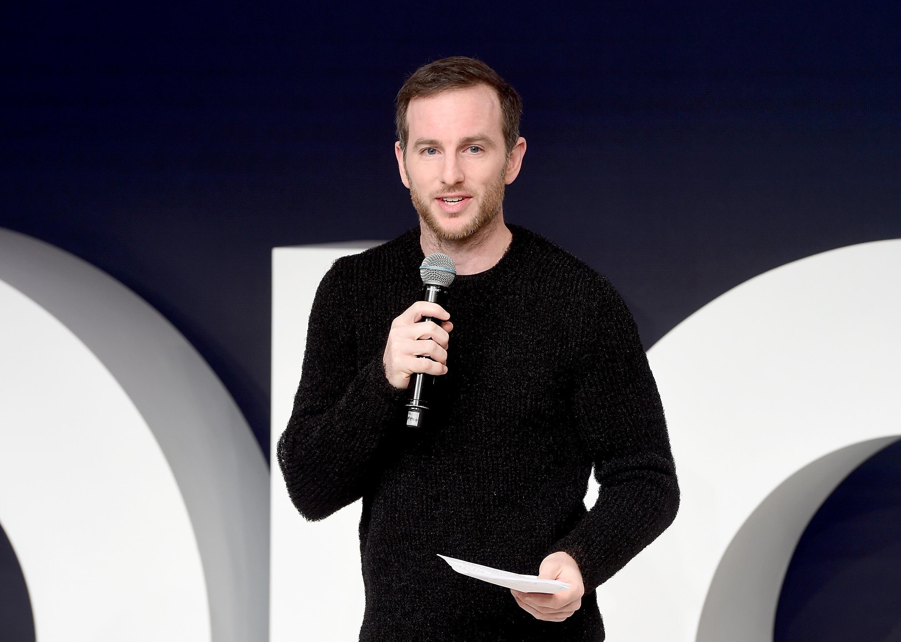 Joe Gebbia in a black sweater with a microphone on stage.