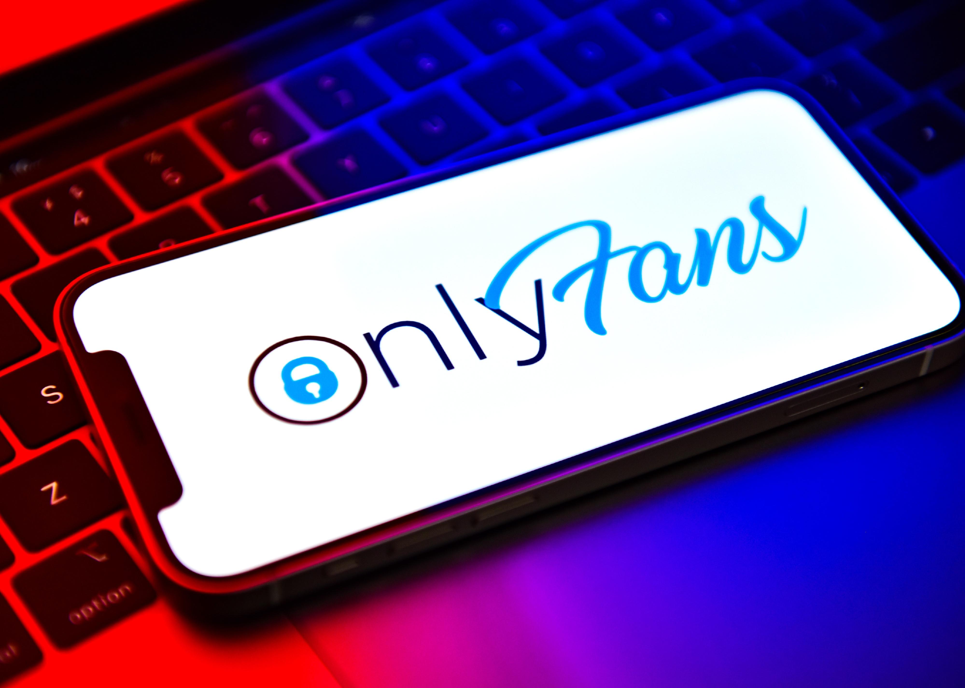 A phone with the OnlyFans app up sitting on a laptop. 