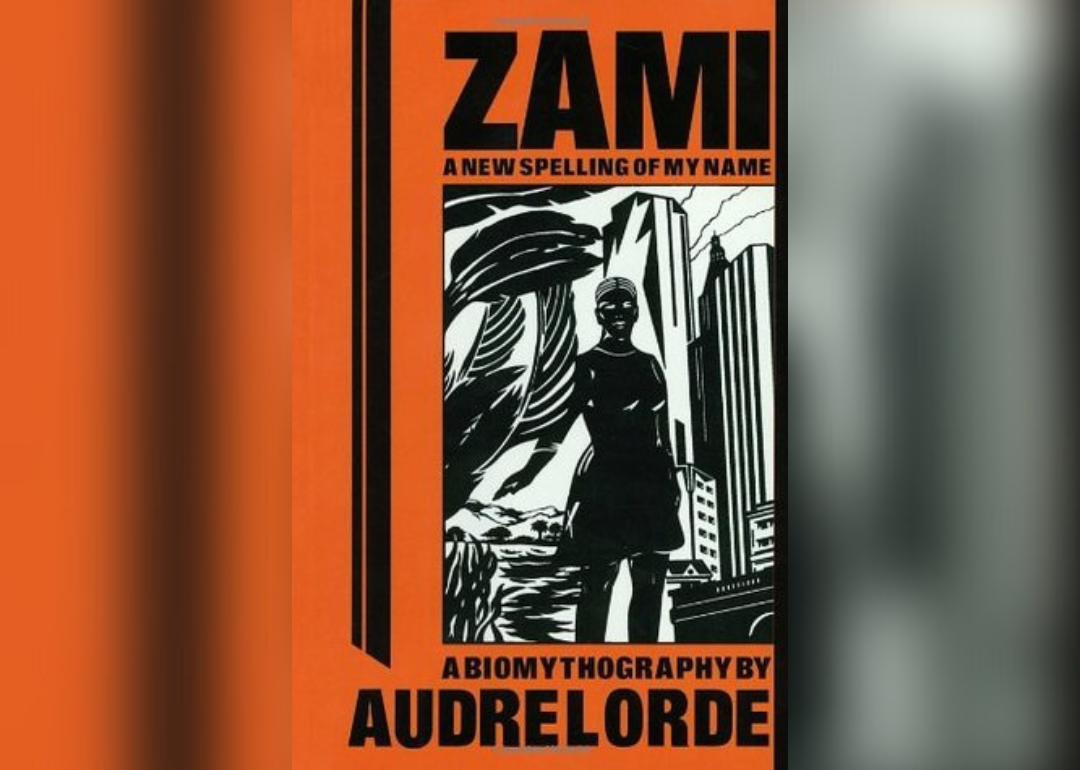 A black drawing of a woman standing next to palm leaves in front of a city.