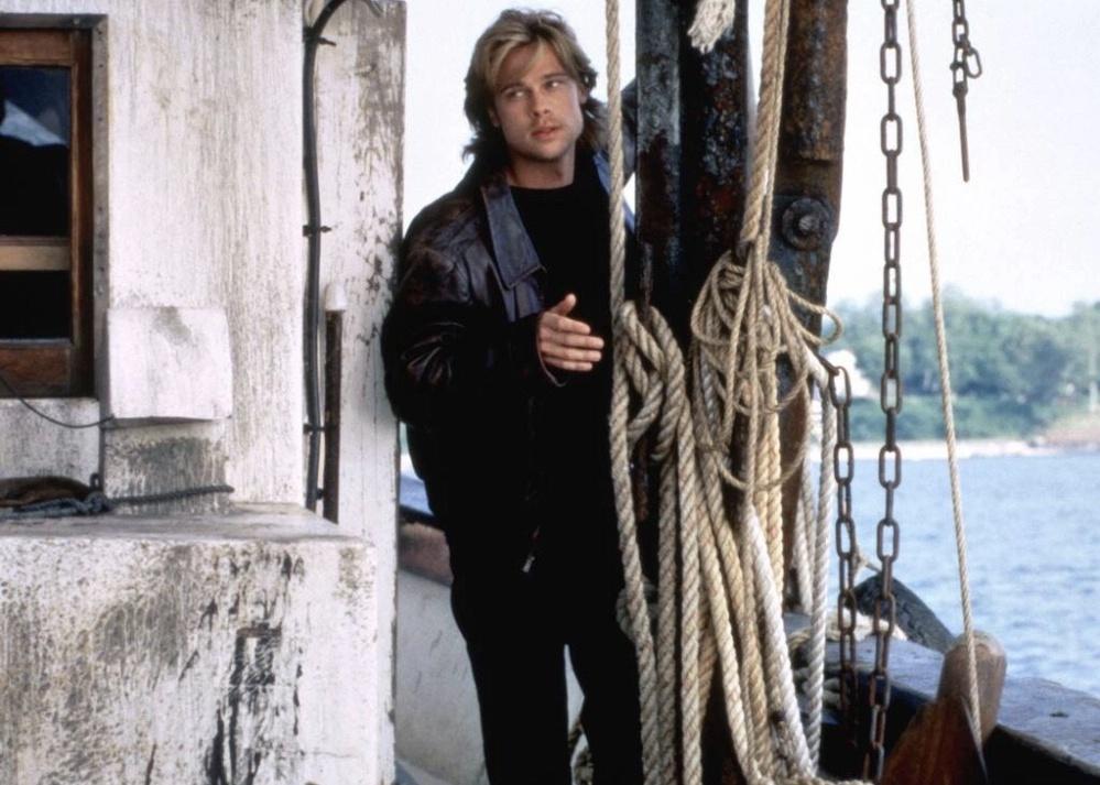Brad Pitt standing behind a rope by the water.