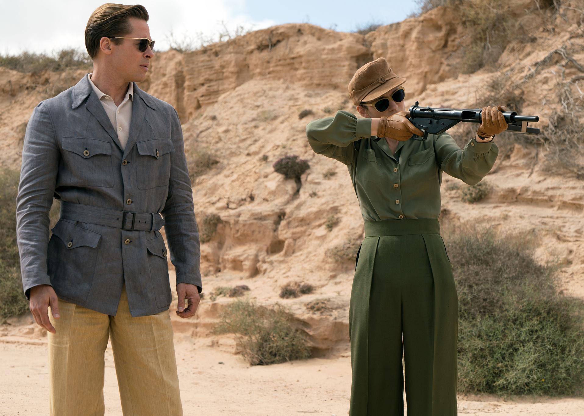 Brad Pitt watches Marion Cotillard shooting a long gun.