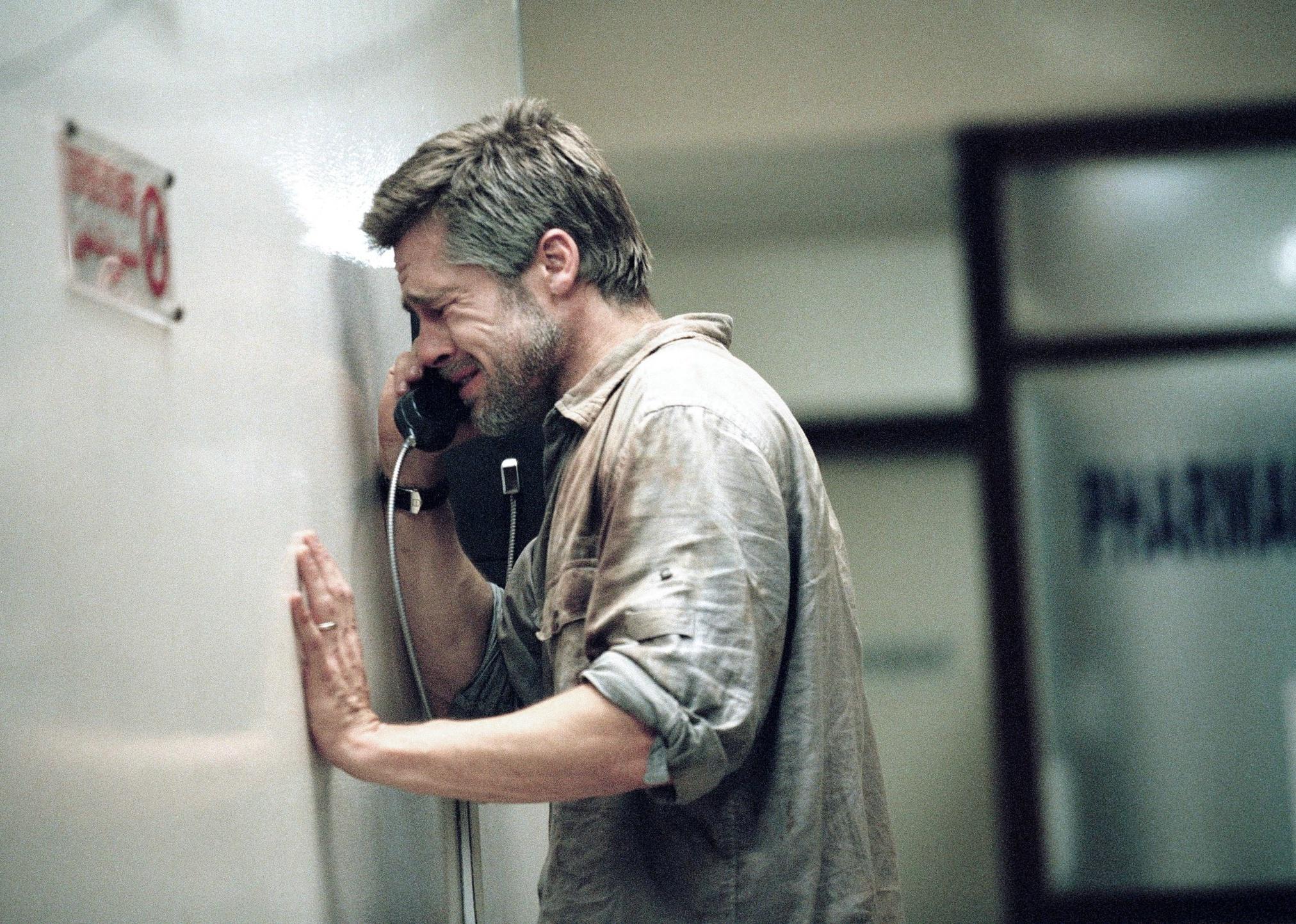 Brad Pitt on a payphone in a hallway crying against the wall.