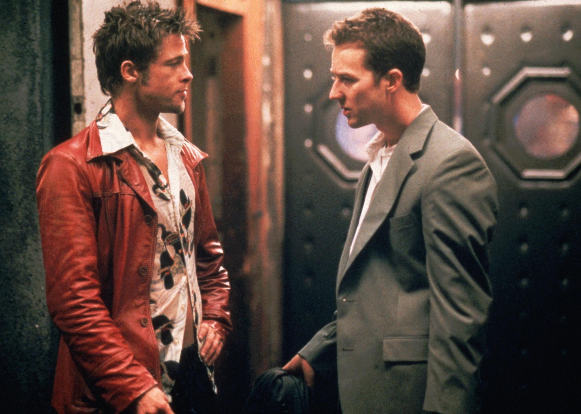 Brad Pitt in a leather jacket talking to Edward Norton.