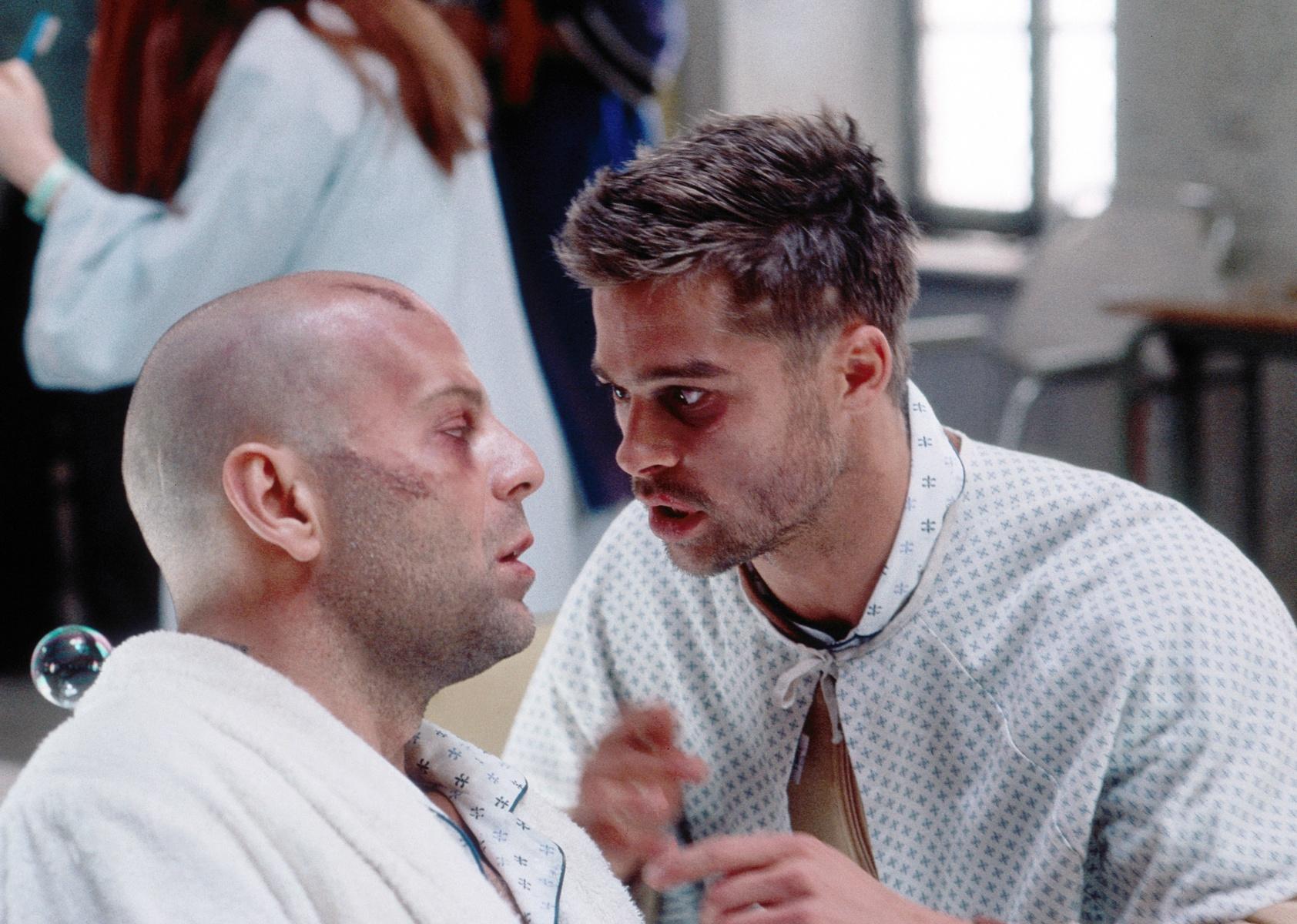 Brad Pitt, in a hospital gown, pleading with Bruce Willis, in a robe.