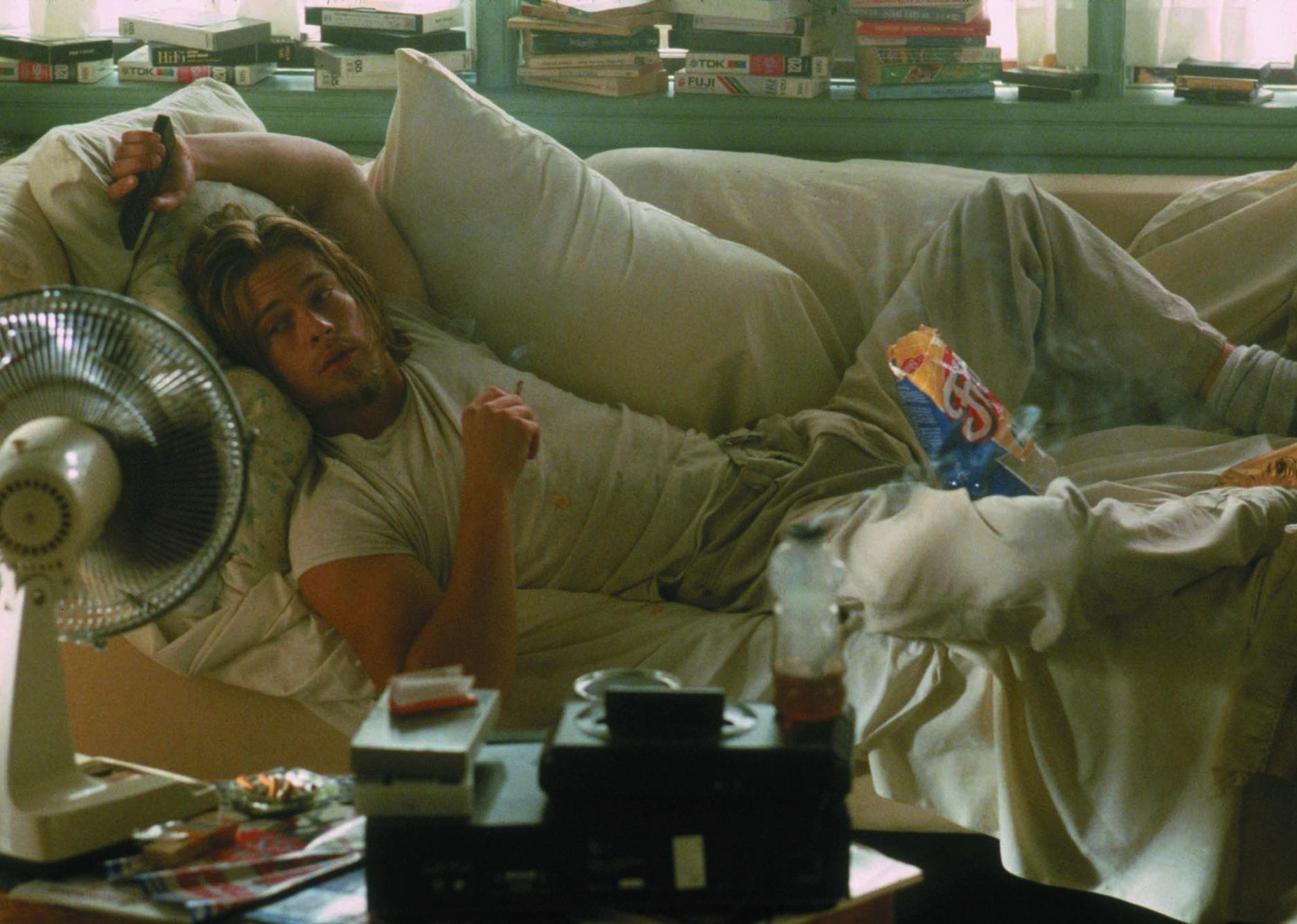 Brad Pitt lying on a couch with food, looking dirty.